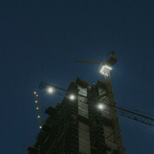 Mobile crane working a night shift on a lit city construction site