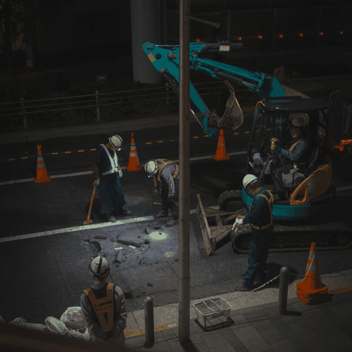 Site crew in high-visibility gear working under artificial light at night