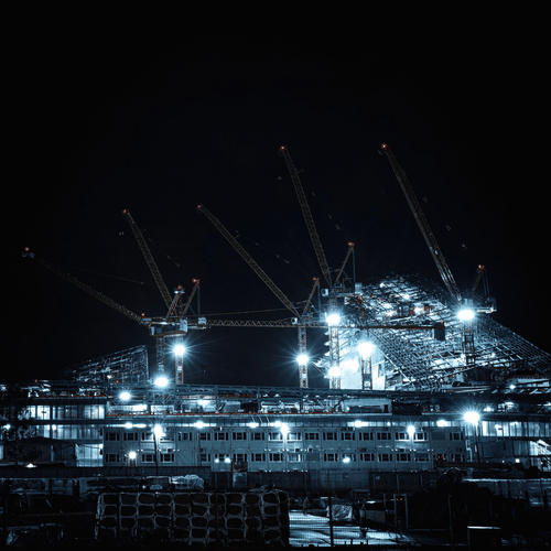 Cranes working a large illuminated worksite after dark
