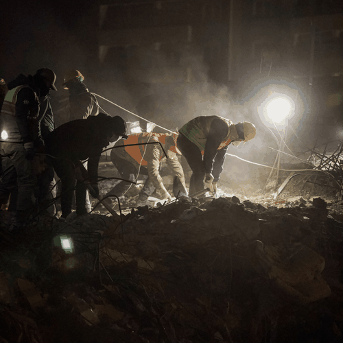 Ground crew working an excavation at night under a portable work light